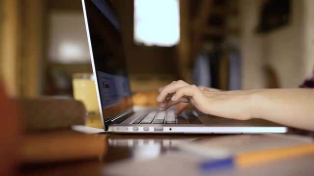 Unrecognizable tenage girl at home, working on notebook, typing