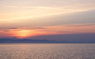 Early morning at dawn of the day with a calm blue sea overlooking the sky and mountains of the other shore,