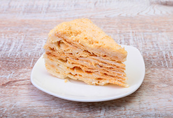 Homemade Napoleon puff cake on plate on wooden table close-up.