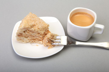 Homemade Napoleon puff cake on plate and traditional espresso coffee isolated on white background. close-up.