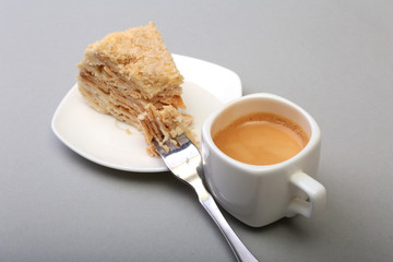 Homemade Napoleon puff cake on plate and traditional espresso coffee isolated on white background. close-up.