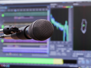 Microphone on the background of the computer monitor. Home recording Studio. Close-up. The focus in the foreground. Blurred background. Software for recording and editing sounds. - obrazy, fototapety, plakaty
