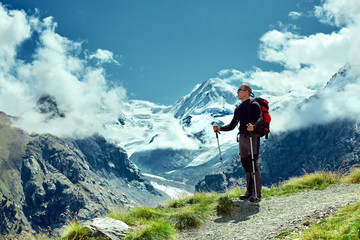 Fototapeta na wymiar hiker at the top of a pass with backpack enjoy sunny day in Alps. Switzerland, Trek near Matterhorn mount.