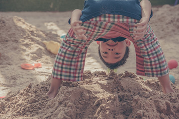 young asian boy   playing in sand pit.