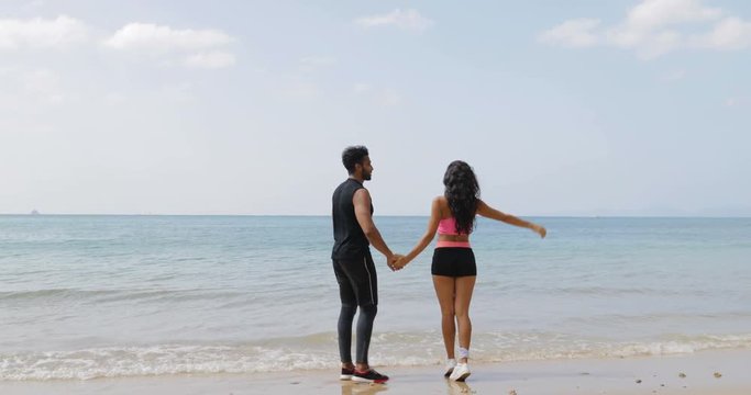 Man And Woman Holding Hands On Beach, Couple In Sportwear Back Rear View Outdoors Slow Motion 60