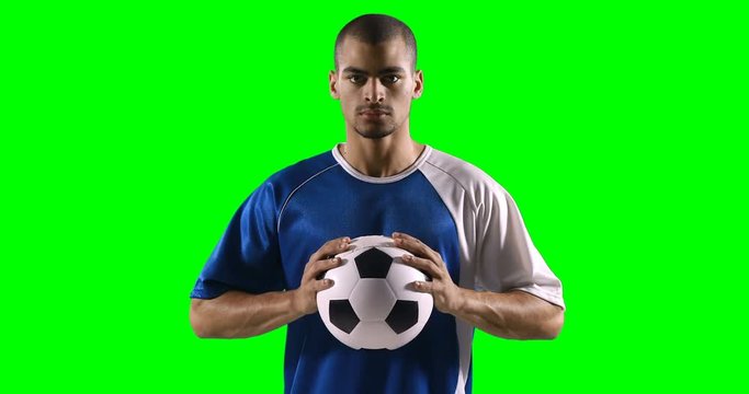 Confident football player holding a football