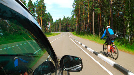 Naklejka premium POV: Car is moving on curving road near a bicycle