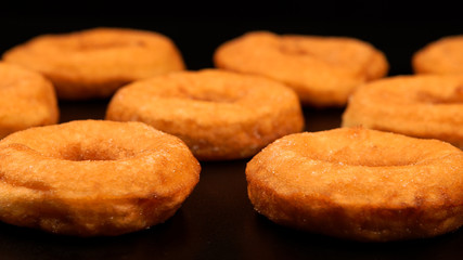 Rows of fried doughnuts on the black table