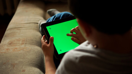 Child using a digital tablet PC with green screen