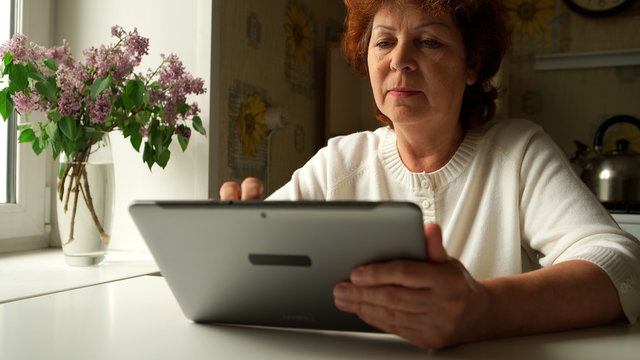 Aged Woman Using A Digital Tablet PC At Home