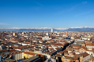 Aerial view of Torino, Italy from the top of the Mole Antonelliana towards the San Paolo Skyscraper (by Renzo Piano) with Alps in the background. Piazza Castello and the royal palace are also visible.