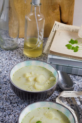 White asparagus soup with coconut milk. Stone table, gray background, books, bottles and wooden board.