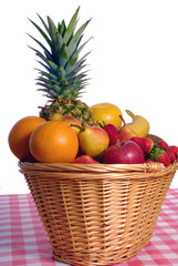 Basket full of various kinds of fruit with red rustic table cloth over white background 