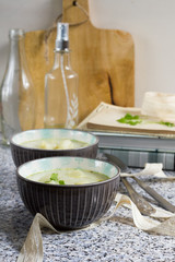 White asparagus soup with coconut milk. Stone table, gray background, books, bottles and wooden board.