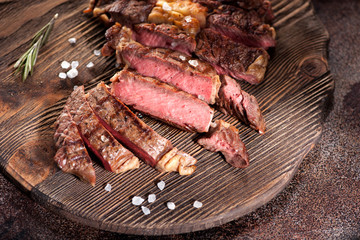Ribeye steak slices with salt and rosemary on a wooden serving board