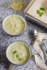 White asparagus soup with coconut milk. Stone table, gray background, books, bottles and wooden board.