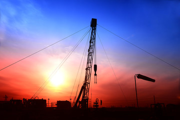 Fototapeta premium Pumping unit in the work, under the background of the setting sun