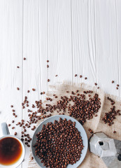 cup of coffee,coffee maker  and coffee beans on a white wooden background
