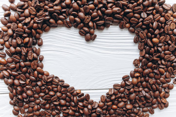 Heart of coffee beans on white wooden background