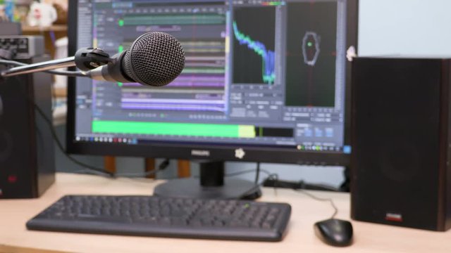 Microphone on the background of the computer monitor. Home recording Studio. Close-up. The focus in the foreground. Blurred background. Software for recording and editing sounds. 4K, UHD, Ultra HD