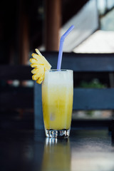 Pineapple juice in a glass, piece of fruit and a tube.