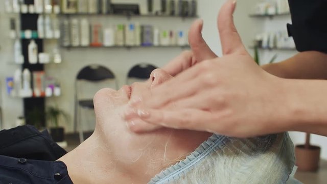 Application and massage of the cream on the face of a woman.