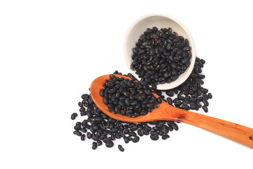 black beans with wooden spoon and in cup closeup on white background