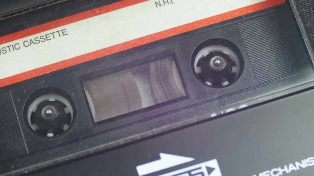 Vintage Audio Tape with White Blank Label is Rotates. Audio Tape. Macro static camera view of vintage audio cassette tape with a blank white label in use sound recording in a cassette player.