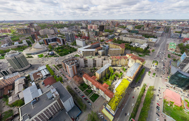 Aerial city view with crossroads and roads, houses, buildings, parks and parking lots, bridges. Copter shot. Panoramic image.