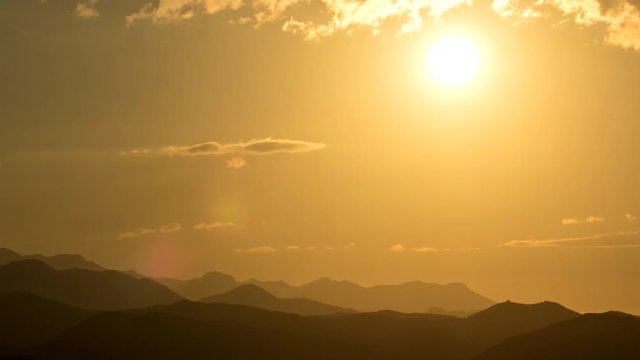Warm orange Sunrise in the early morning over the mountains in Spain. Perfect weather, almost no clouds, beautiful color change while the sun makes its way. High quality 4K zoom out time lapse.