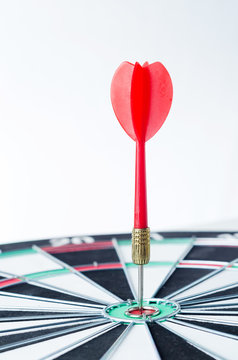 Close up shot red dart arrow on center of dartboard, metaphor to target success