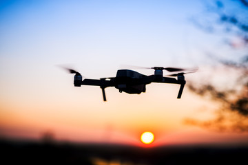 Drone flying into the sunset. Silhouette of drone against colorful sky.