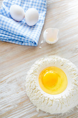 Ingredients and tools for baking - flour, eggs and glass of milk on the wooden rustic table background, selective focus