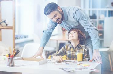Cheerful father standing behind little son