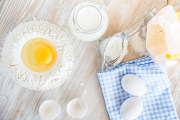 Ingredients and tools for baking - flour, eggs and glass of milk on the wooden rustic table background, selective focus