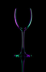 Silhouette wineglass on a black background with colored reflexes.