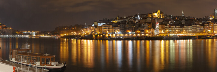Panorama of Ribeira and Old town of Porto with mirror reflections in the Douro River at night, Portugal, Portugal.