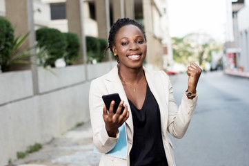 Fototapeta premium Young businesswoman manisfesting her joy when she saw a transfer in her smart phone