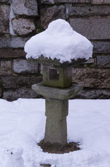 A stone lantern and moss covered with snow on top.