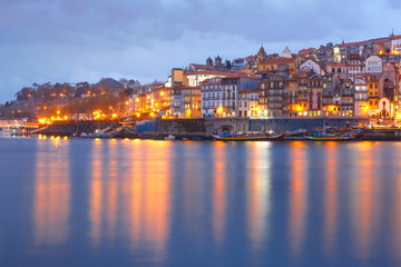 Fototapeta na wymiar Ribeira and Old town of Porto with mirror reflections in the Douro River during evening blue hour, Portugal, Portugal.