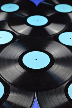 pile of old black vinyl records with blank cyan labels on blue background