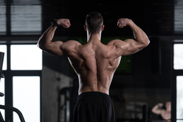 Fototapeta na wymiar Muscular Man Flexing Back Muscles Pose