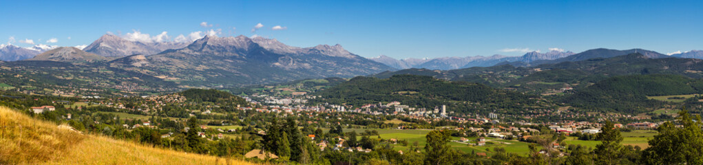 Fototapeta na wymiar Panoramic summer view of the city of Gap in the Hautes Alpes with surrounding mountains and peaks. Southern French Alps, Paca region, France