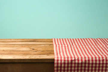 Empty wooden table covered with red checked tablecloth. Background for product montage display
