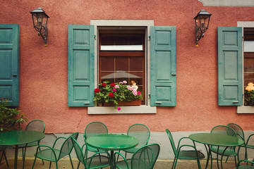 Fototapeta na wymiar Outdoor restaurant tables over building wall background. Old Europen city urban detail. Retro filter effect