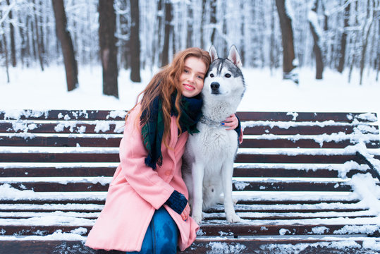 Happy woman sitting on the bench with husky