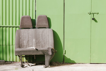 Discarded car seats in front of a green garage door