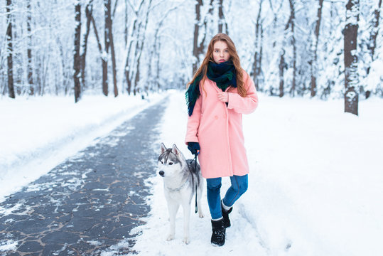 Young woman walks in the park with siberian husky