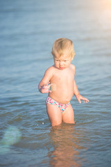 Baby playing on the sandy beach and in sea water. Cute little kid with toys on sand tropical beach. Ocean coast.