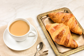 Cup of coffee with fresh croissants